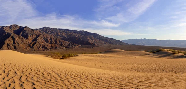 Sand dunes in a desert landscape in Death Valley California.  The vast barren land is dry and arid due to droughts result of global warming and climate change.