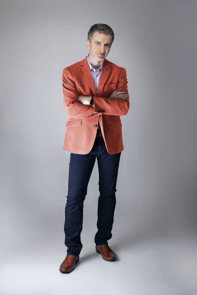 Middle-aged fashion model wearing coral colored sports coat or jacket for the fall clothing collection.  Depicts modern colorful apparel style for 2019.