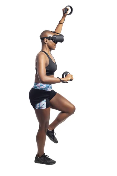 Athletic black female playing a vr video game pretending to do mountain climbing in virtual reality.  She is gaming while exercising to depict technology and healthy activities.