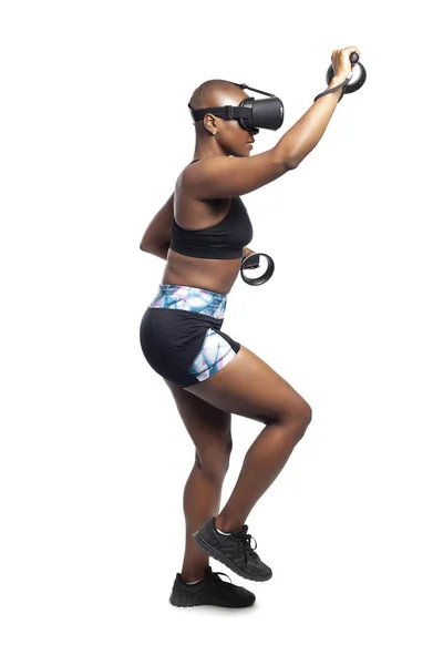 Athletic black female playing a vr video game pretending to do mountain climbing in virtual reality.  She is gaming while exercising to depict technology and healthy activities.