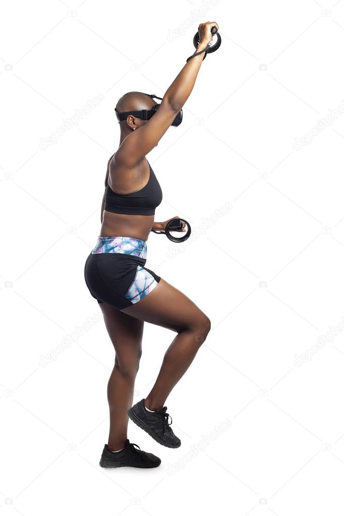 Athletic black female playing a vr video game pretending to do mountain climbing in virtual reality.  She is gaming while exercising to depict technology and healthy activities. 