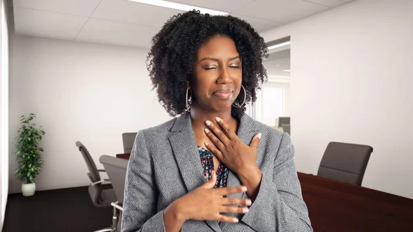 Black African American businesswoman in an office looking sick with sore throat.  She is an owner or an executive of the workplace.  Depicts careers and startup business.