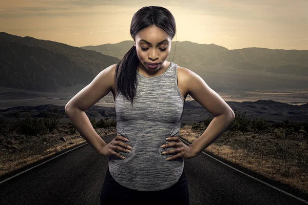アスレチックブラックアフリカ系アメリカ人の女性ランナーやジョガーは 背景に日没時に道路と意欲的な表情でポーズをとるために休んでいます マラソンスポーツ中の持久力と決意を描く — ストック写真