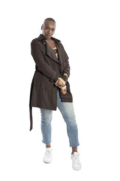 Black African American fashion model with bald hairstyle confidently posing with a coffee brown colored jacket for fall collection.  Depicts fashion design and clothing apparel