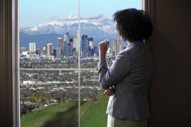 Siyah kadın iş kadını Los Angeles'ta bir ofisin penceresinden dışarı bakıyor. O kentsel gelişim ya da bir belediye başkanı ya da vali imar yasaları planlama düşünen bir kadın mimar gibi görünüyor. 