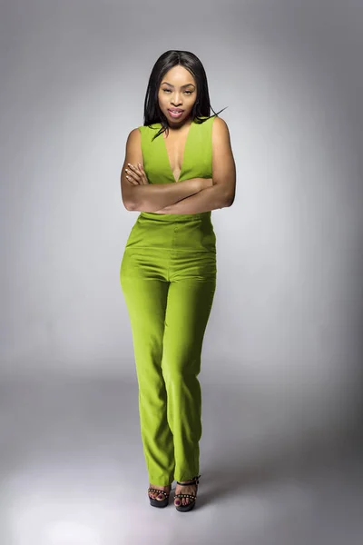 African American fashion model posing with lime green v-neck jumpsuit in a studio for fall collection catalog.  She is confidently showing the sleeveless top and matching pants.