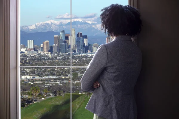 カリフォルニア州ロサンゼルスのダウンタウンを望むオフィスの窓から心配や疲れを見ている黒人女性ビジネスウーマン 彼女はスタートアップのビジネスオーナーや政治家や都市計画の建築家のように見えます — ストック写真
