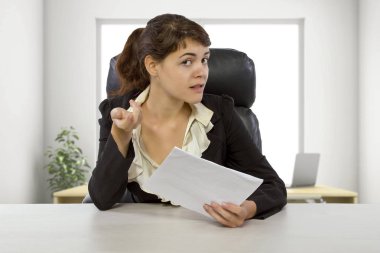 Genç beyaz kadın stajyer bir ofis masasında yorgun ya da stresli görünüyor. Ödenmemiş bir staj yapıyor ve öğrenci kredisi borcu konusunda endişeli görünüyor..  