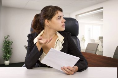 Genç beyaz kadın stajyer bir ofis masasında yorgun ya da stresli görünüyor. Ödenmemiş bir staj yapıyor ve öğrenci kredisi borcu konusunda endişeli görünüyor..  