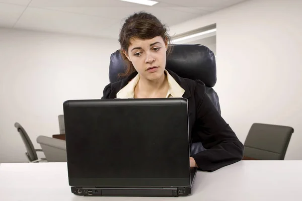 Young Caucasian female intern looking tired or stressed out in an office desk.  She is doing an unpaid internship and looking worried about student loan debt.