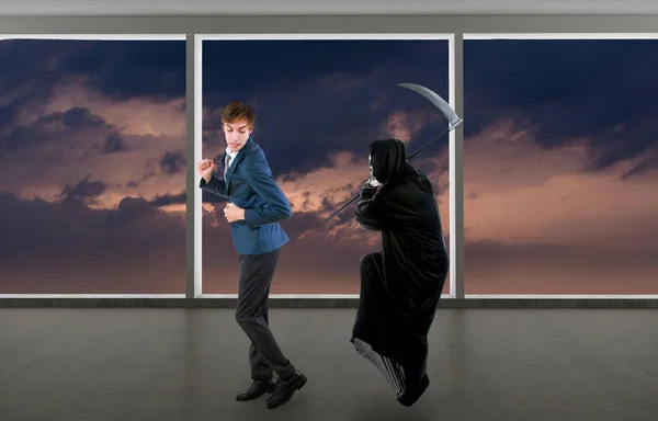Man in a Halloween grim reaper ghost costume chasing, mocking and making fun of scared businessman running away.  Can also depict death following a man as a metaphor for life insurance.