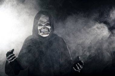 Sisli sisin içinden korkunç görünümlü Azrail hayaleti geliyor. Korkunç iblis, ölüm ve kötülüğü tasvir eder ve yaygın bir Cadılar Bayramı temasıdır..  