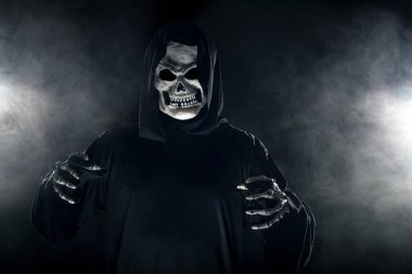 Sisli sisin içinden korkunç görünümlü Azrail hayaleti geliyor. Korkunç iblis, ölüm ve kötülüğü tasvir eder ve yaygın bir Cadılar Bayramı temasıdır..  