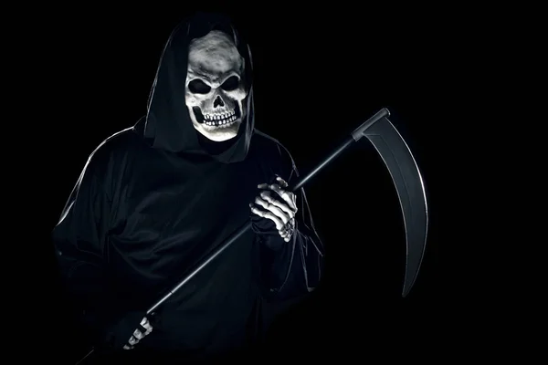 Grim Reaper ghost coming out of the shadows with a scythe or sickle.  The scary demon or monster depicts Halloween and Day of the Dead holiday.