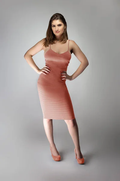 自信的女时尚模特穿着褪了色的粉色珊瑚或肉色的夏装在工作室里摆出一副目录风格的肖像 这套衣服无袖 配合脚的鞋子 — 图库照片