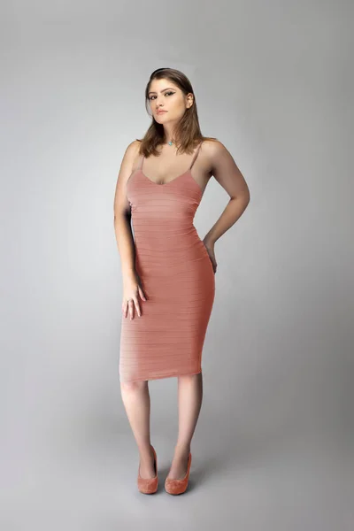 自信的女时尚模特穿着褪了色的粉色珊瑚或肉色的夏装在工作室里摆出一副目录风格的肖像 这套衣服无袖 配合脚的鞋子 — 图库照片