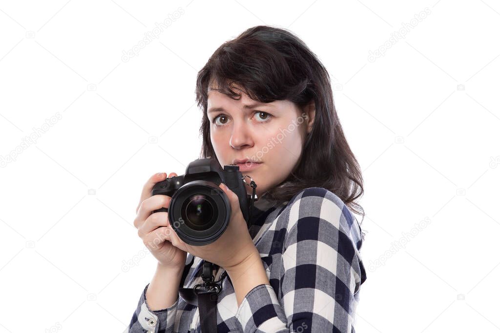 Young female freelance professional photographer or art student or photojournalist on a white background holding a camera. She is scared or doubtful