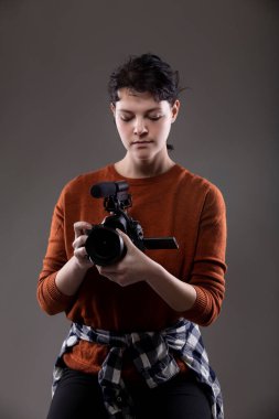 Video bloglarında kullanılan bir video kamerayı elinde tutan bir kadın içerik yaratıcının portresi. Amatör bir film yapımcısı ya da sanat öğrencisi.