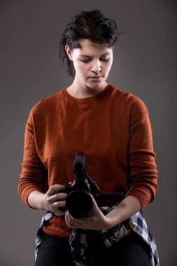 Video bloglarında kullanılan bir video kamerayı elinde tutan bir kadın içerik yaratıcının portresi. Amatör bir film yapımcısı ya da sanat öğrencisi.