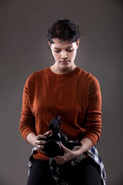 Video bloglarında kullanılan bir video kamerayı elinde tutan bir kadın içerik yaratıcının portresi. Amatör bir film yapımcısı ya da sanat öğrencisi.