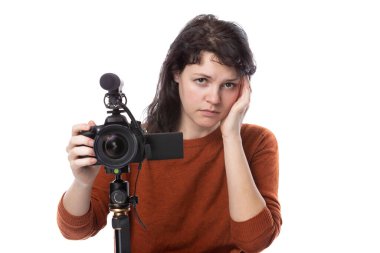 Kamera ve mikrofonu olan genç bir kadın ya da beyaz arka planda online içerik yaratıcısı. Sinema öğrencisi ya da hasta görünümlü serbest çalışan birine benziyor.  