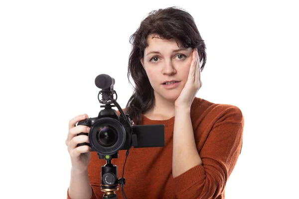 年轻女性带着相机和麦克风作为电影制作人或网上内容创作人 看上去很震惊或困惑 她看起来像个电影专业的学生或自由职业者 — 图库照片