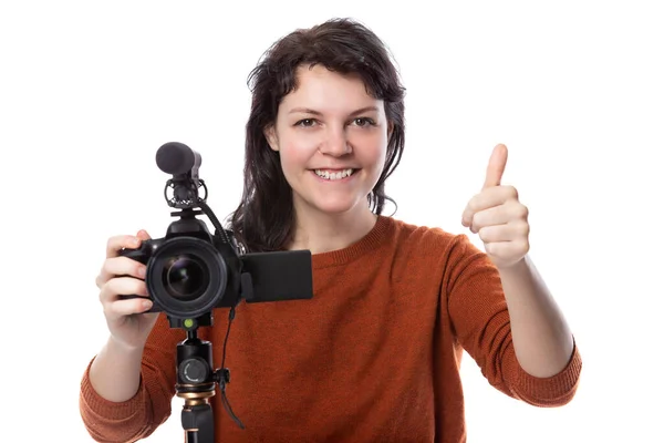 年轻女性带着相机和麦克风作为电影制作人或在线内容创建者做着一个竖起大拇指的手势 她看起来像个电影专业的学生或自由职业者 — 图库照片