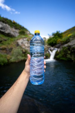 Su şişesi ve bir el şelalede sağlık hizmetleri yürüyüşü.