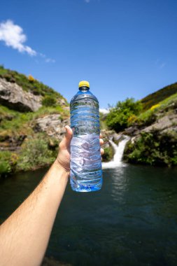 Su şişesi ve bir el şelalede sağlık hizmetleri yürüyüşü.