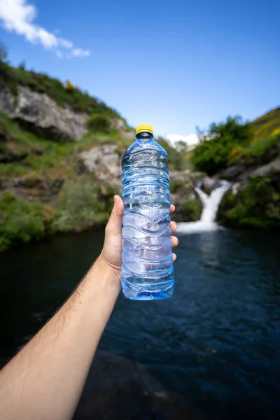 Water bottle and a hand in the nature waterfall healthcare sport trekking