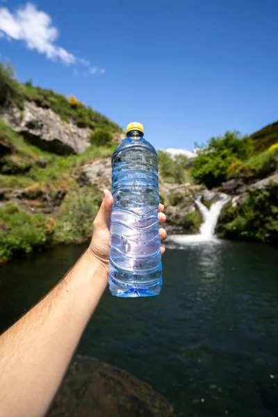 Water bottle and a hand in the nature waterfall healthcare sport trekking