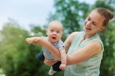 Annem parkta yeni doğmuş bir bebekle eğleniyor. Kollarına sardı. Gülüyorlar.. 