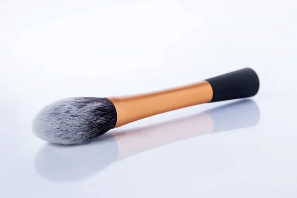 Cepillo de maquillaje grueso con asa de oro y impulso suave. Cepillo para maquillaje sobre fondo blanco — Foto de Stock