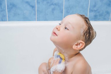 Çocuk küvette yıkanır, bebek boynu köpükle yıkanır.