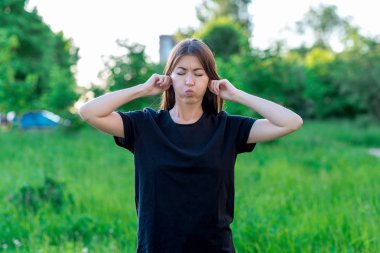 Esmer kız doğa Park'ta. Kulakları holding eller. Kahvaltılık yanakları. Kapris ve aptallık kavramı. Duygusal hoşnutsuzluk eğlenceli.