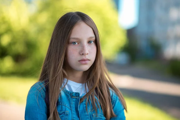 Nastoletnie dziewczyny z piękne długie włosy. Piegi na twarzy. Stawia na kamera patrzy. Latem w parku na świeżym powietrzu. Starannie marzy w głowie. — Zdjęcie stockowe