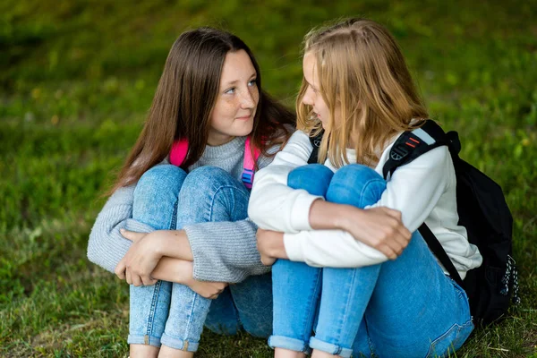 Deux adolescentes. L'été dans la nature. Ils sont assis sur l'herbe. Communiquez entre vous. Il parle d'une conversation intime. Meilleurs amis. Vie privée des adultes . — Photo