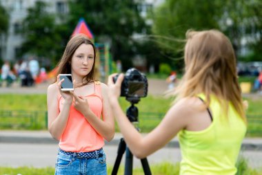 İki kız arkadaş. Doğa yazın. Bize telefon avantajları hakkında söyle. Belgili tanımlık smartphone avantajları. Kayıt vlog ve blog abone. Internet için kayıt video ders. Kullanma fotoğraf makinesi tripod ile.