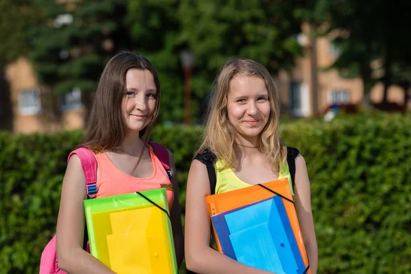 Two girls schoolgirl. Summer in nature. Smile happily. Ready for school lessons. In hands of a folder with notebooks. He rests after school. Best girlfriends. — Stock Photo, Image
