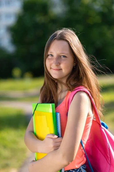 Piękna brunetka dziewczyna. Lato w przyrodzie. Odpoczywa po szkole. W rękach notebooka są podręczników. Z tyłu jest plecak. Szczęśliwy uśmiechający się. Cieszy się reszta. — Zdjęcie stockowe