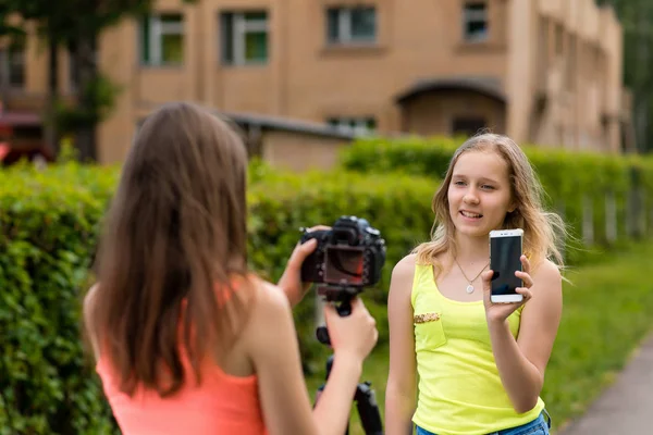 Two girls are bloggers. Young journalists. Describes advantages of phone. Make a broadcast on the Internet. Record vlog and blog subscribers. Record video lesson for Internet. Use camera with tripod. — Stock Photo, Image