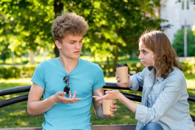 Bir kız bir adamla doğa parkında yaz. Elinde bardak kahve ve çay ile tutar. Eller yanlış anlama iletişim jest. Birbirinizle konuşmak kavramı. Kızgınlık iddia.