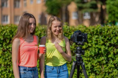 İki kız öğrenci. Yaz sokak. Mutlu bir şekilde gülümsüyor. Kayıt vlog ve blog abone. Internet için kayıt video ders. Kullanma fotoğraf makinesi tripod ile.