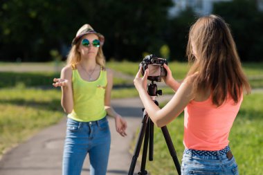 İki kız arkadaş. Doğa yazın. Onlar internette yayın. Röportaj kavramları. Kayıt vlog ve blog abone. Internet için kayıt video ders. Kullanma fotoğraf makinesi tripod ile.