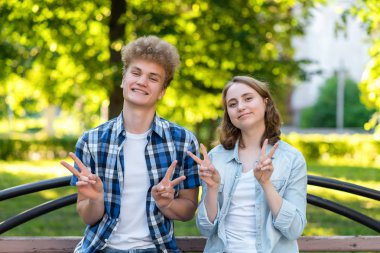 Doğada bir parkta yaz aylarında bir kızla bir adam. Mutlu duygusal gülümseyen mutlu. El jestleri Merhaba gösterir. Kavramı başarı ve iyi şanslar. Okuldan sonra mutlu öğrenciler.