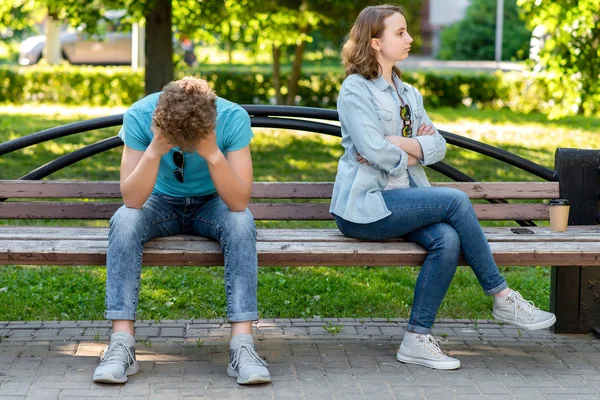 A guy with a girl is sitting on a park bench in summer. The concept is ruined by family life. Quarrels and misunderstandings in the relationship. The silence of the problem in family life. — Stock Photo, Image