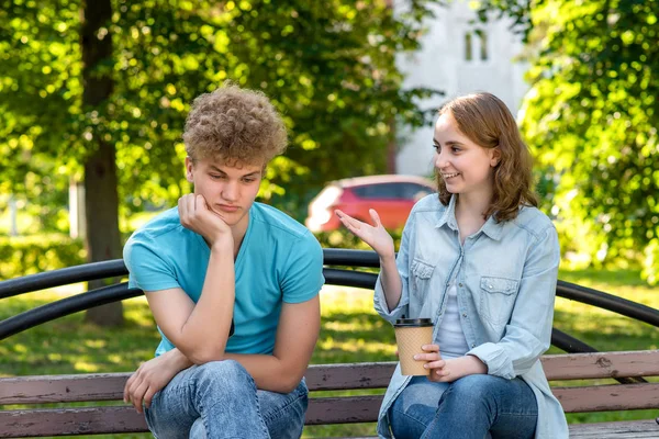 El hombre está cansado de hablar. La chica está hablando con el tipo. Reticencia a escuchar al interlocutor. Un tipo con una chica en verano en un parque en la naturaleza. Problemas en la relación . —  Fotos de Stock