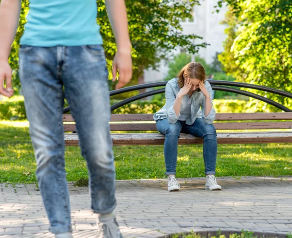 The guy leaves the young girl. This park is in nature. A girl is sad and crying is sitting on a bench. The concept of problem in the family and breaking the relationship. — Stock Photo, Image