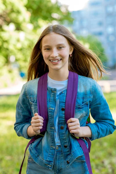 美しい女子高生の女の子。放課後夏。故郷を。背後にあるバックパック。彼女はジーンズの服を着てください。幸せそうに笑って帰宅します。. — ストック写真