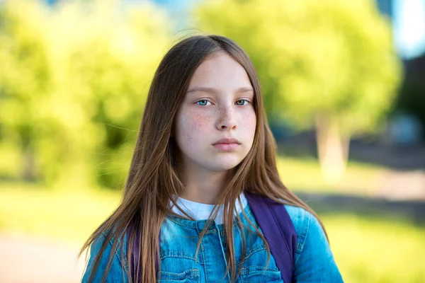 Девочка школьница летом в парке. Крупный план портрета девушки с длинными волосами. Веснушки на лице. Эмоции серьезный уверенный взгляд . — стоковое фото